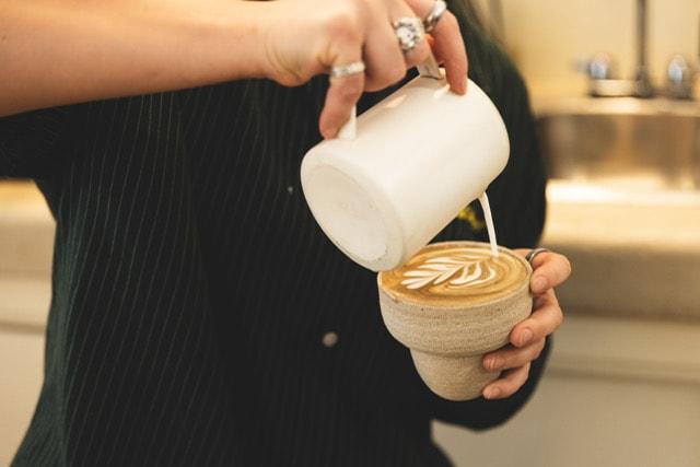 Barista pouring latte art into a specialty coffee at Rakia Coffee in Jacksonville.